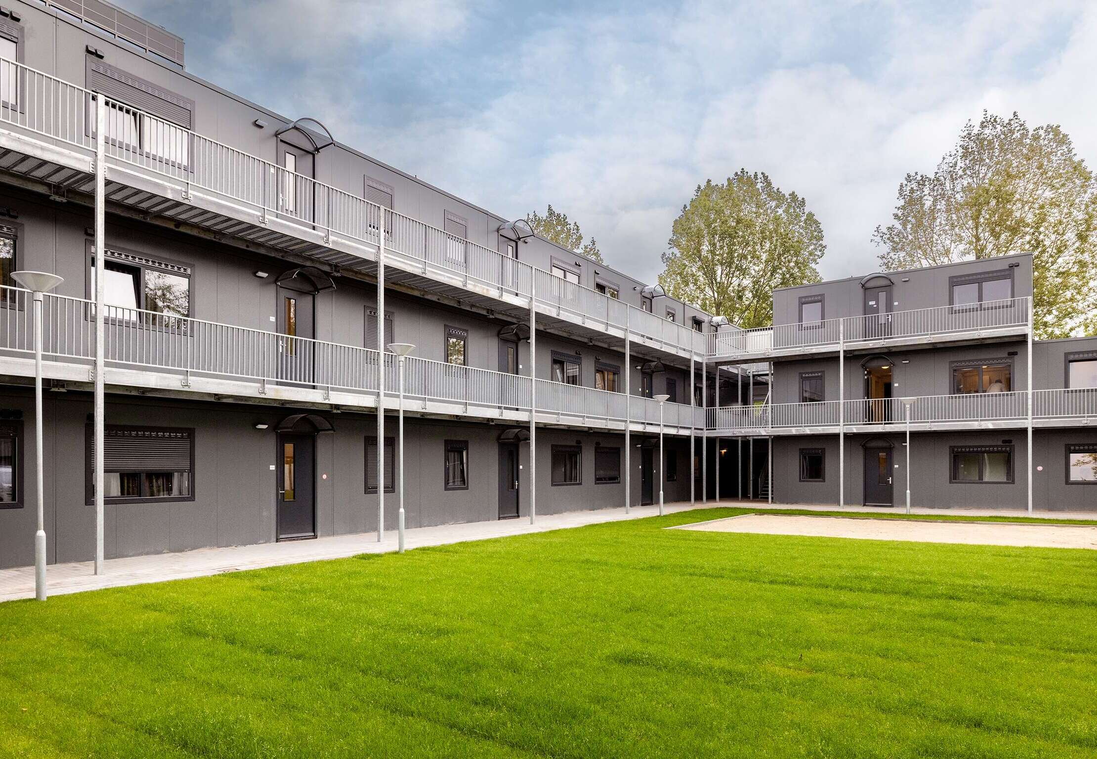 Noodopvang opgebouwd uit grijze modulaire units met een verzorgd grasveld.